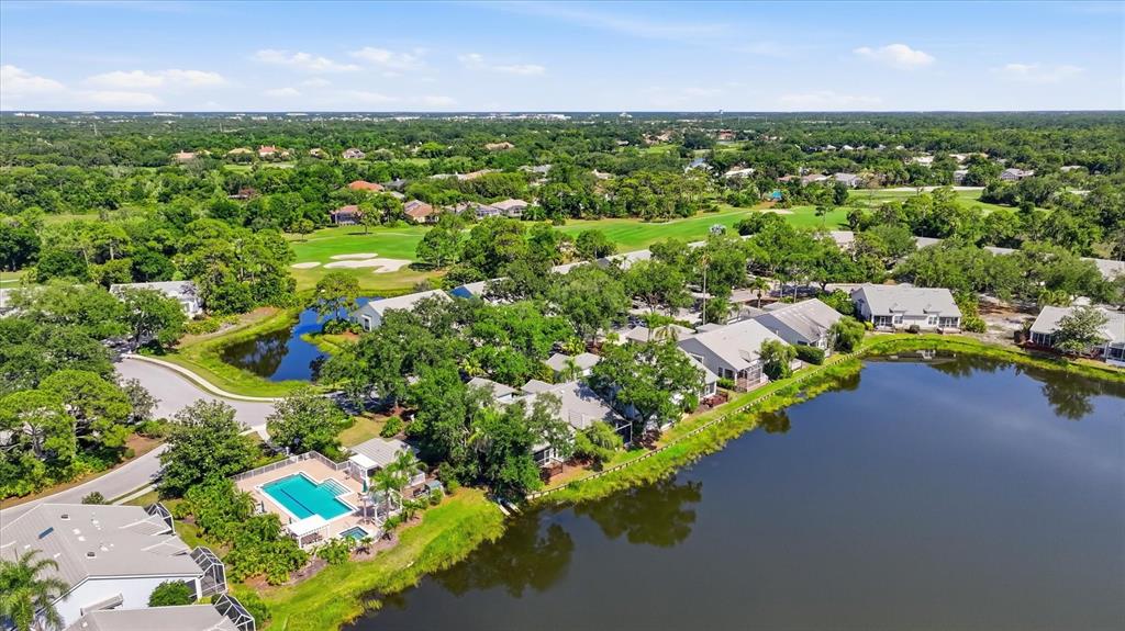An aerial view shows a residential community with a swimming pool, lake, and golf course — 7706 WHITEBRIDGE GLEN, UNIVERSITY PARK, FL