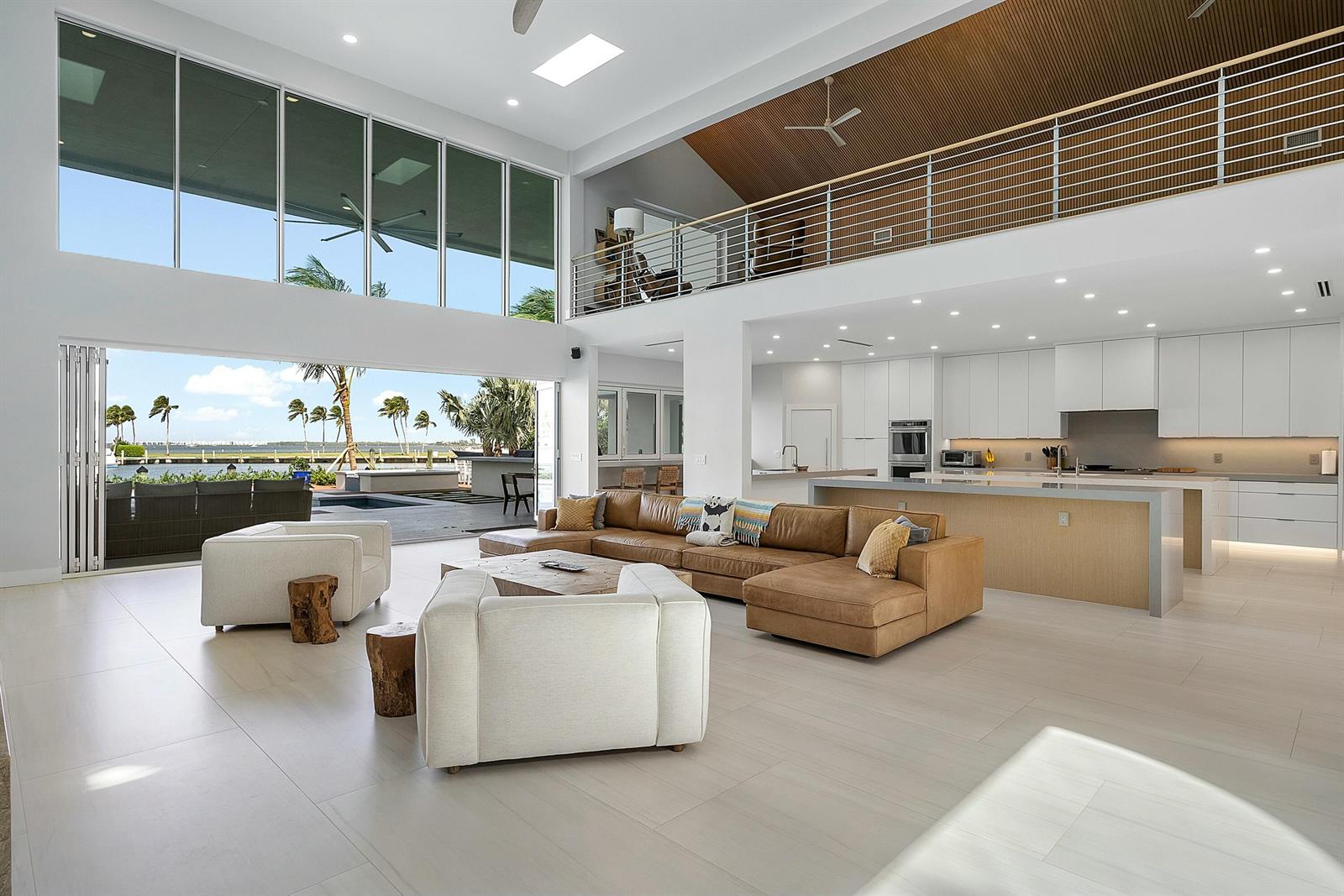 A spacious open-concept living room and kitchen featuring large glass doors overlooking a waterfront patio — 6879 SE South Marina Way, Stuart FL 34996, STUART, FL