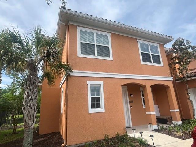 A two-story orange stucco townhouse features a palm tree in the front yard — 5758 LESABRE DRIVE, KISSIMMEE, FL