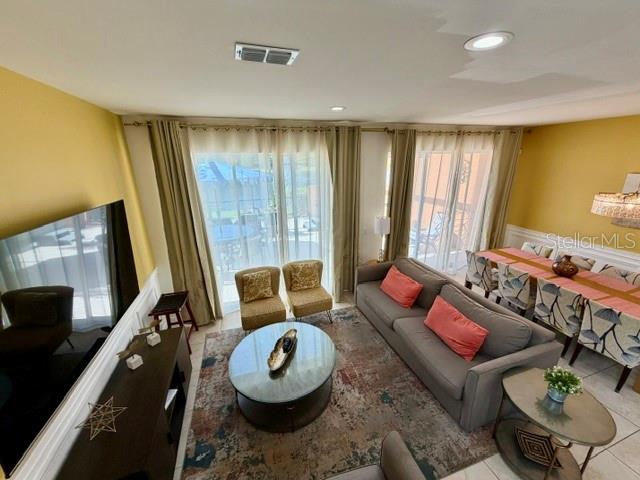 A living room with a gray sofa, two armchairs, a dining area, and sliding glass doors — 5758 LESABRE DRIVE, KISSIMMEE, FL