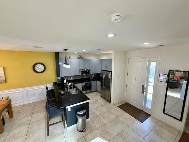 A kitchen with a dark island, stainless steel appliances, and light tile flooring — 5758 LESABRE DRIVE, KISSIMMEE, FL