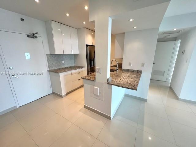 A kitchen features white cabinetry, granite countertops, and light-colored tile flooring — 1000 West Ave # 07, Miami Beach FL 33139, MIAMI BEACH, FL