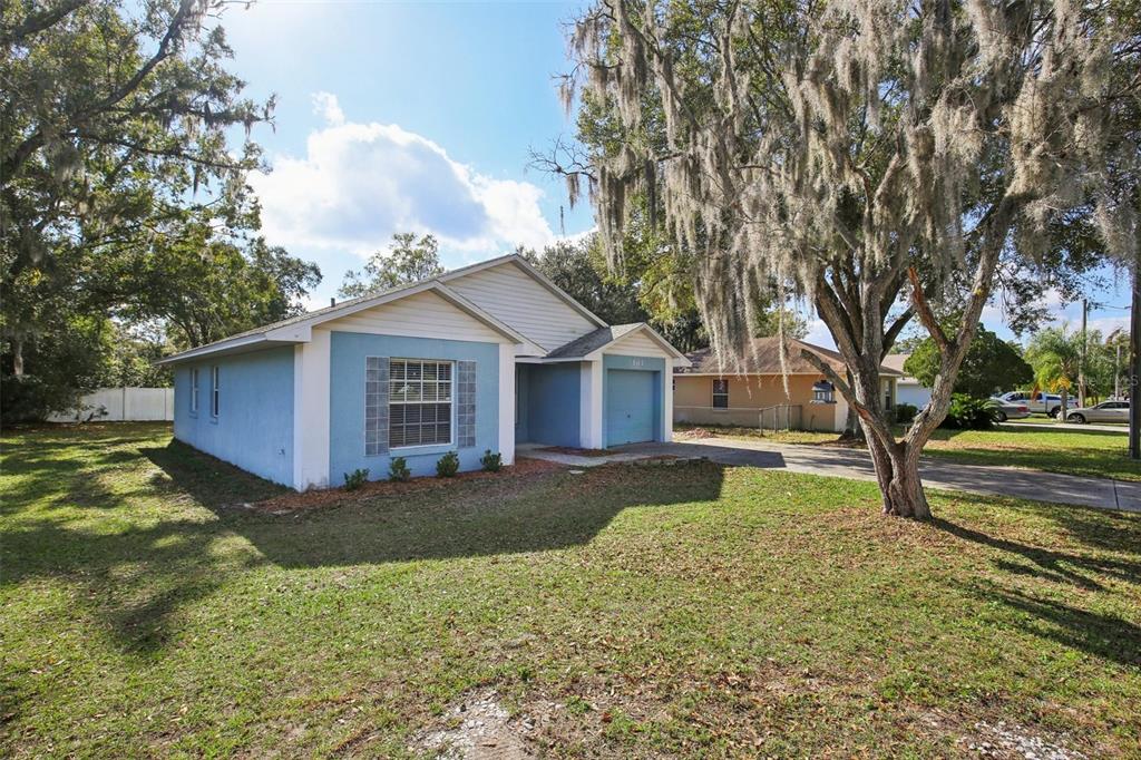 A single-story house with light blue stucco, white trim, a red front door, and garage — 3501 W REYNOLDS STREET, PLANT CITY, FL