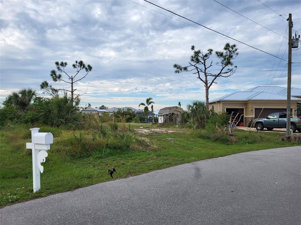 A vacant, grassy residential lot sits next to a house with a gray pickup truck — 10610 RIVERSIDE ROAD, PORT CHARLOTTE, FL