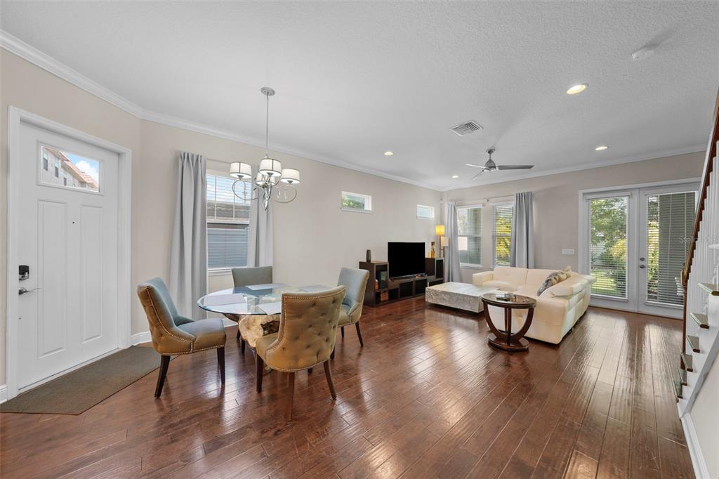 An open-concept living and dining area features hardwood floors, a glass dining table, and furniture — 214 S HABANA AVENUE UNIT 1, TAMPA, FL