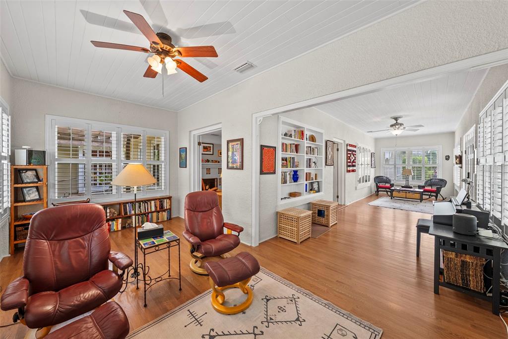 A living area with wood floors, a ceiling fan, bookshelves, and two leather recliners — 2915 W ANGELES STREET, TAMPA, FL