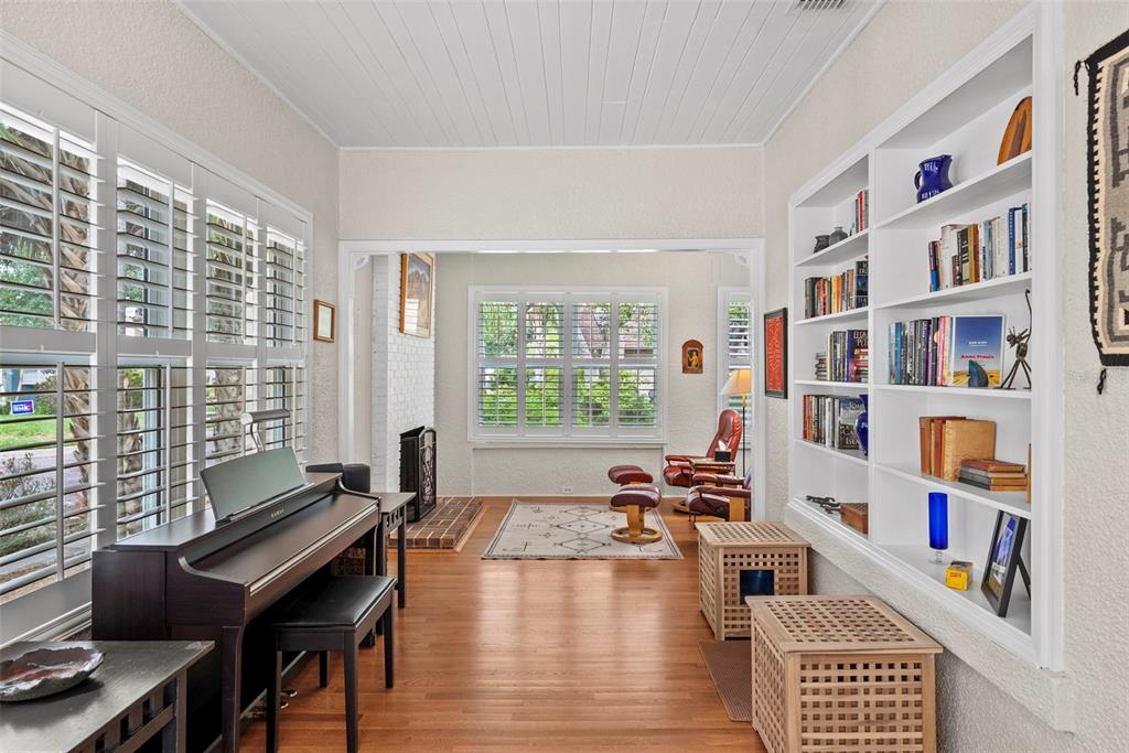 A sunroom with a piano, built-in bookshelves, hardwood floors, and a fireplace — 2915 W ANGELES STREET, TAMPA, FL