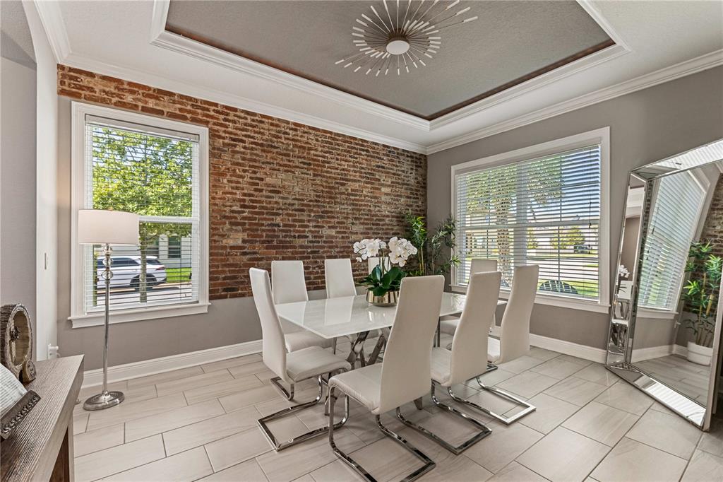 A dining room features a brick accent wall, a white table, and modern chairs — 9225 HOLLISTON CREEK PLACE, WINTER GARDEN, FL