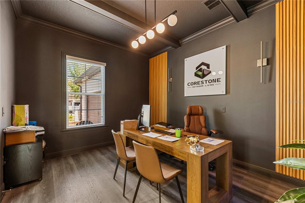 An office features dark walls, wood-look flooring, a wooden desk, and a company logo sign — 9225 HOLLISTON CREEK PLACE, WINTER GARDEN, FL
