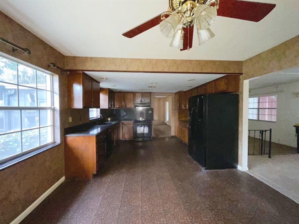 A kitchen with wooden cabinets, dark countertops, a black refrigerator, and a ceiling fan — 603 W OCALA STREET, UMATILLA, FL