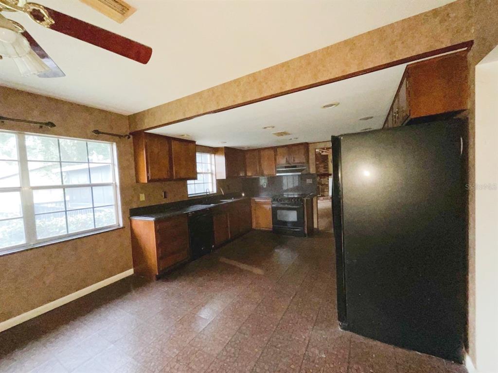 A kitchen features dark wood cabinets, black appliances, and brown patterned flooring — 603 W OCALA STREET, UMATILLA, FL