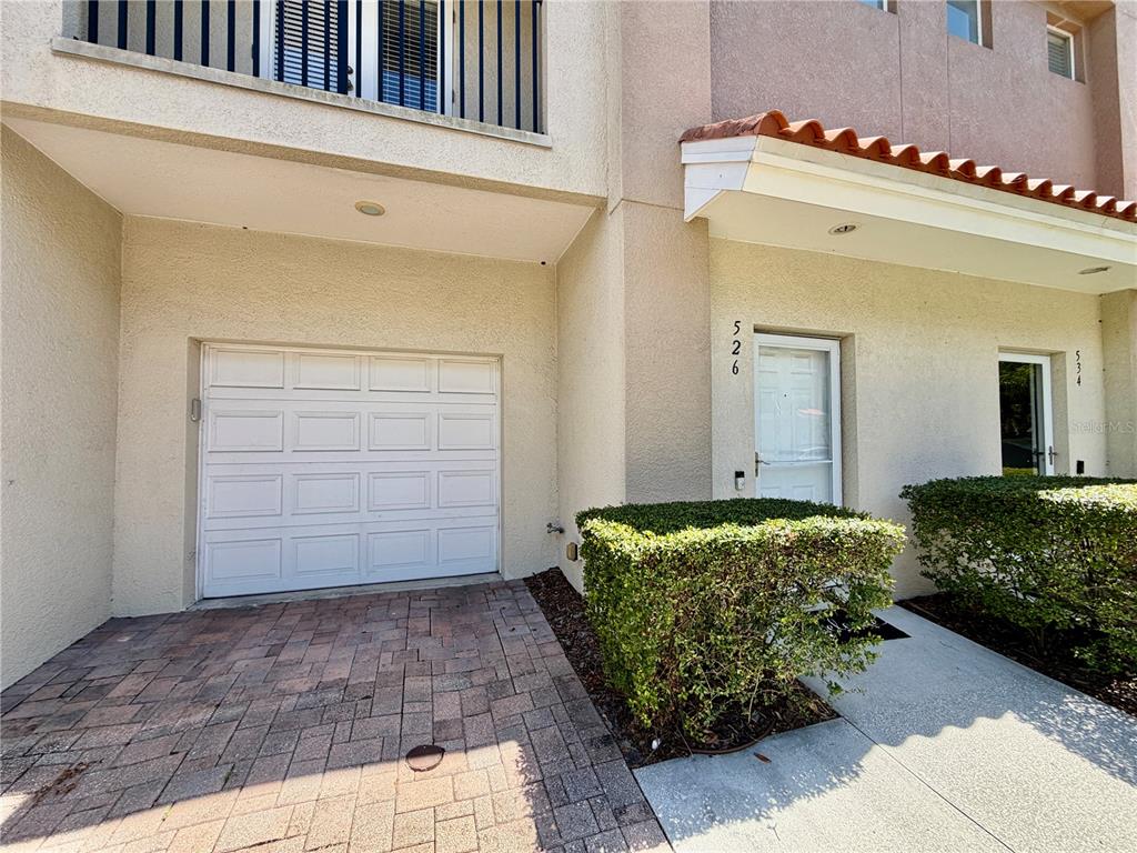 A townhouse exterior features a white garage door, a front entrance, and a small hedge — 526 101ST AVENUE N, ST PETERSBURG, FL