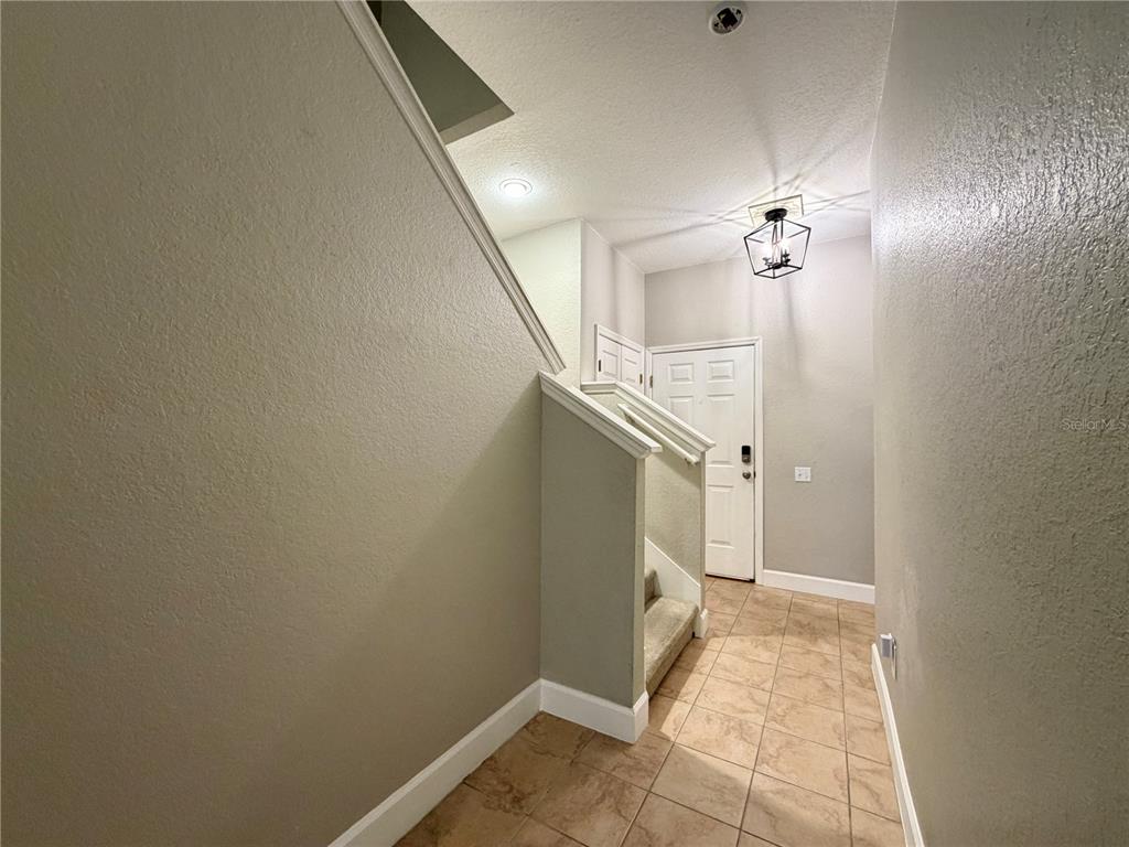 A tiled entryway features a staircase with carpeted steps and a modern hanging light fixture — 526 101ST AVENUE N, ST PETERSBURG, FL