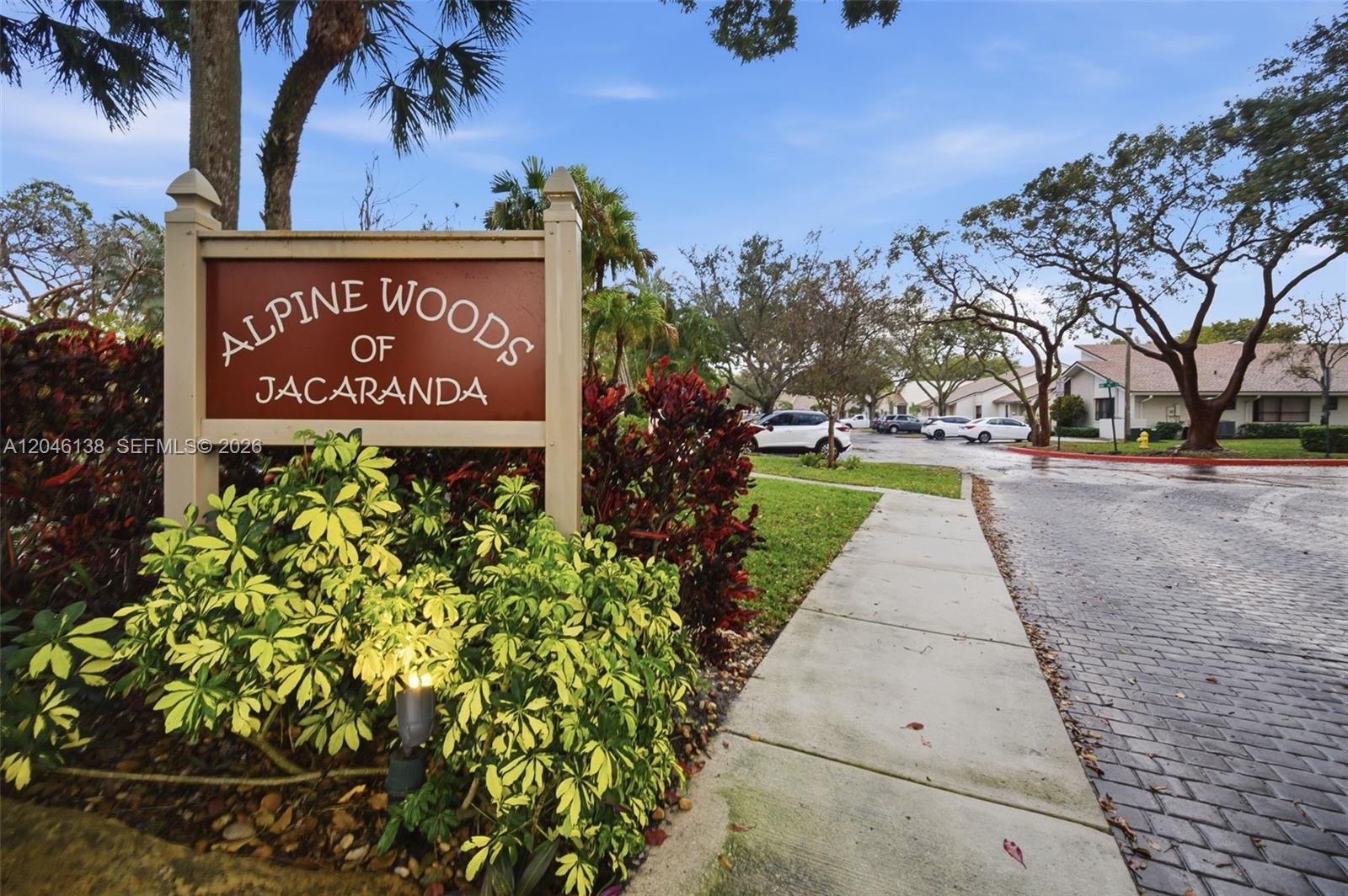 A sign for Alpine Woods of Jacaranda stands beside a sidewalk and a paved road — 7924 NW 10th St, Plantation FL 33322, PLANTATION, FL