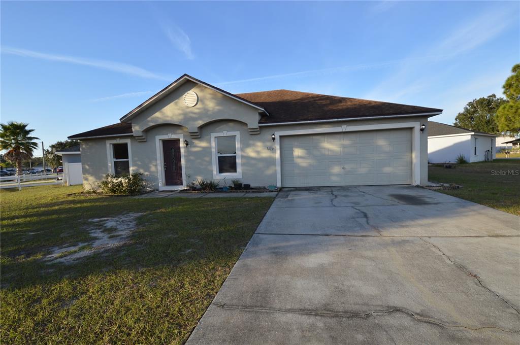 A single-story house with a beige stucco exterior, a two-car garage, and a concrete driveway — 1617 PERDIDO COURT, KISSIMMEE, FL