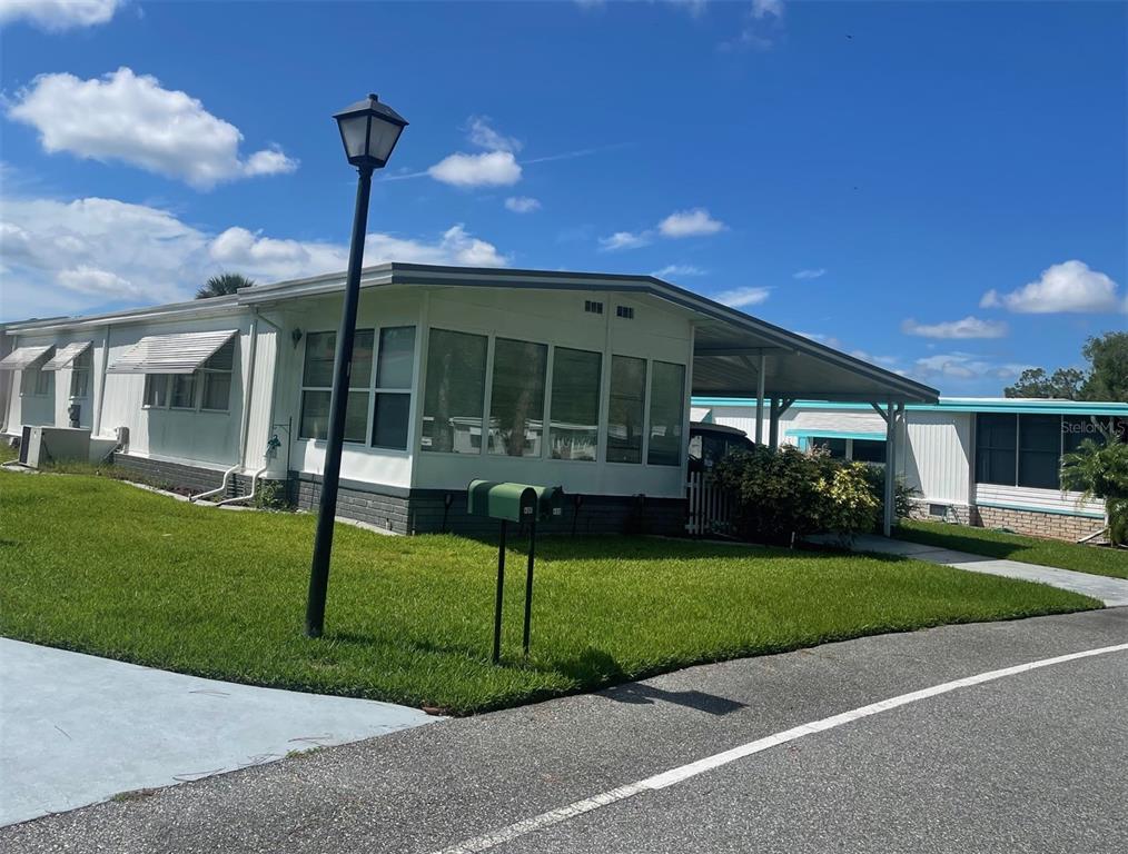 A single-story manufactured home with a white exterior, a carport, and a green mailbox — 408 HAWTHORNE BOULEVARD, LEESBURG, FL