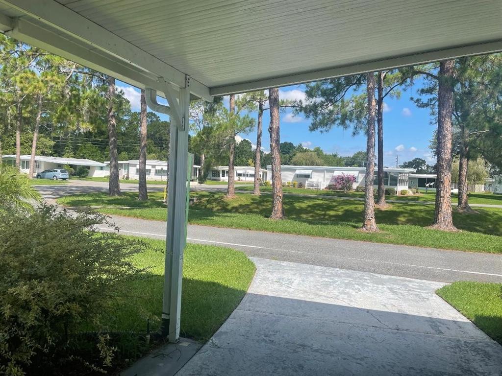 A view from a covered porch looking out toward a street and neighboring mobile homes — 408 HAWTHORNE BOULEVARD, LEESBURG, FL