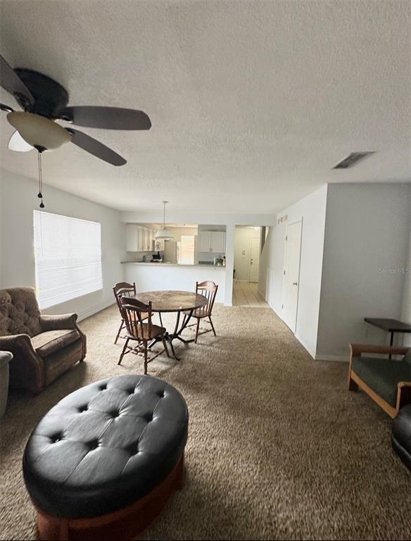 A living and dining area features beige carpeting, a ceiling fan, and an open kitchen — 2306 SW 42ND DRIVE UNIT 140, GAINESVILLE, FL