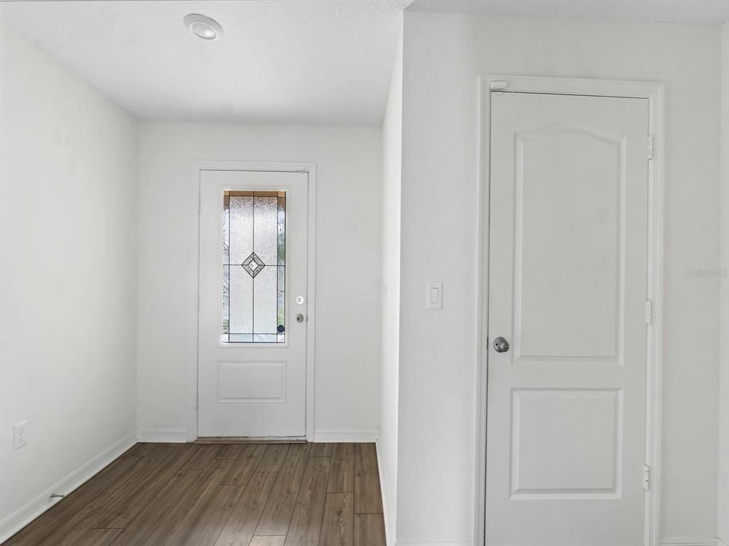 An entryway features white walls, wood-look flooring, a front door with glass, and a closet — 1730 WYNFORD CIRCLE, TAVARES, FL