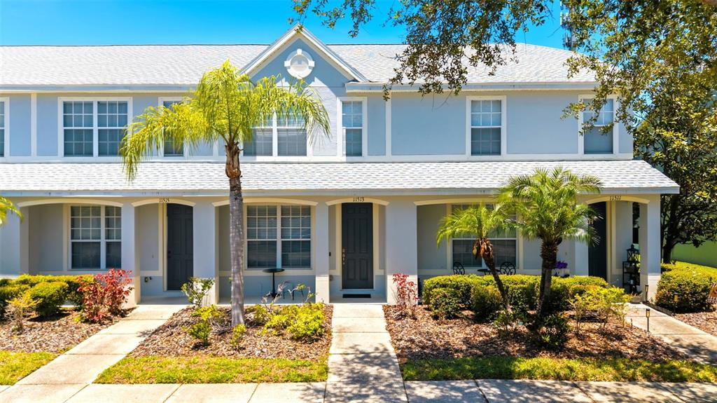 A two-story townhouse exterior features light blue siding, white trim, and two palm trees — 11513 DECLARATION DRIVE, TAMPA, FL