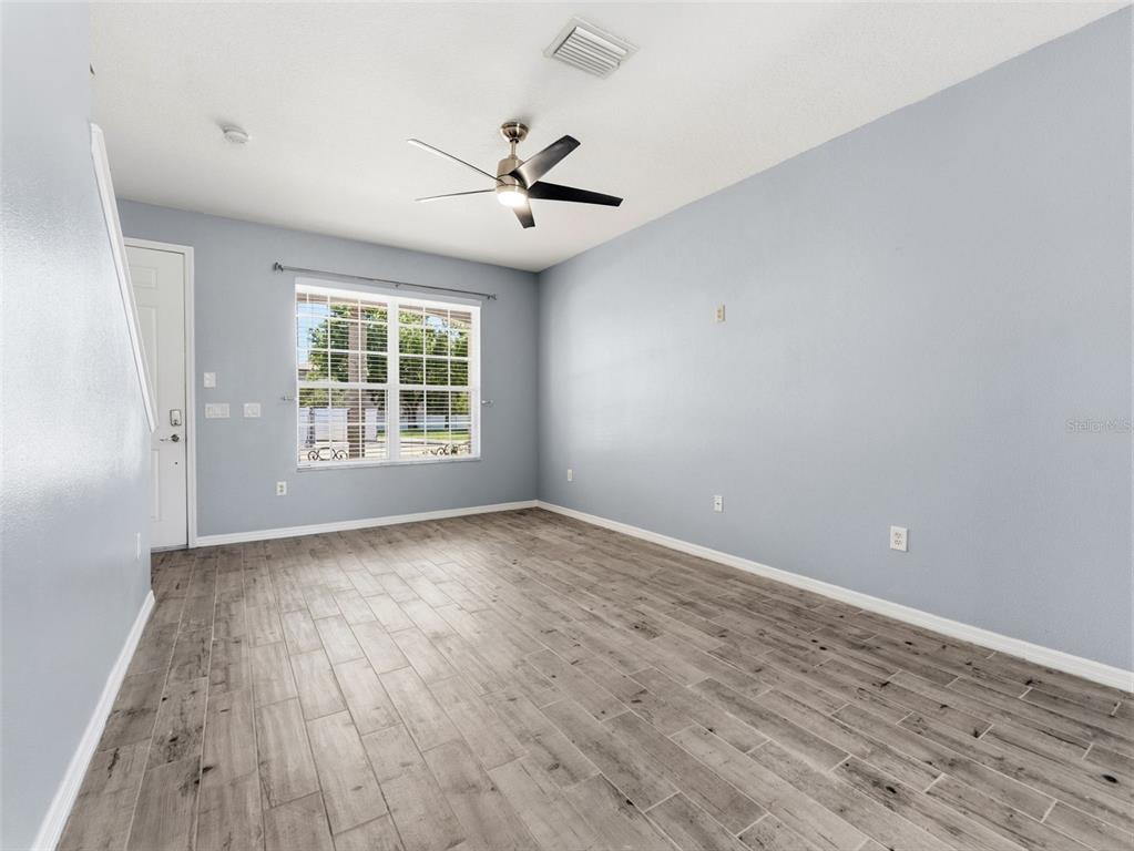 An empty room with light blue walls, wood-look tile flooring, and a ceiling fan — 11513 DECLARATION DRIVE, TAMPA, FL