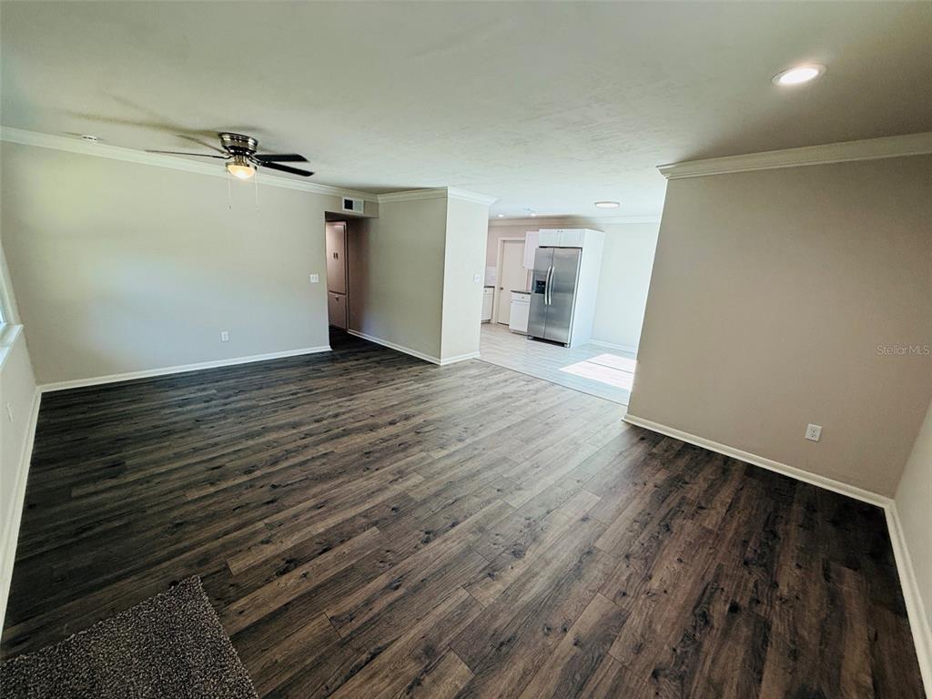 A living room with dark wood-look flooring leads to a kitchen with stainless steel appliances — 1312 NE 28TH AVENUE, GAINESVILLE, FL