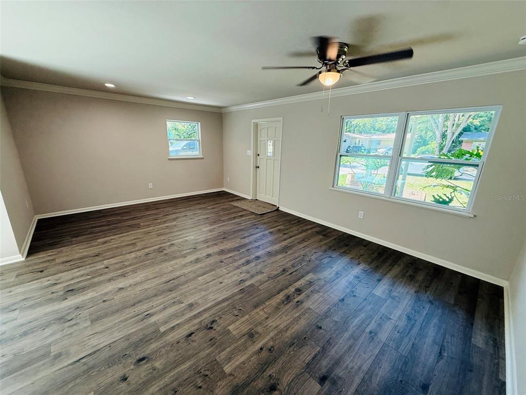 A living room features dark wood-look flooring, light gray walls, and a ceiling fan — 1312 NE 28TH AVENUE, GAINESVILLE, FL