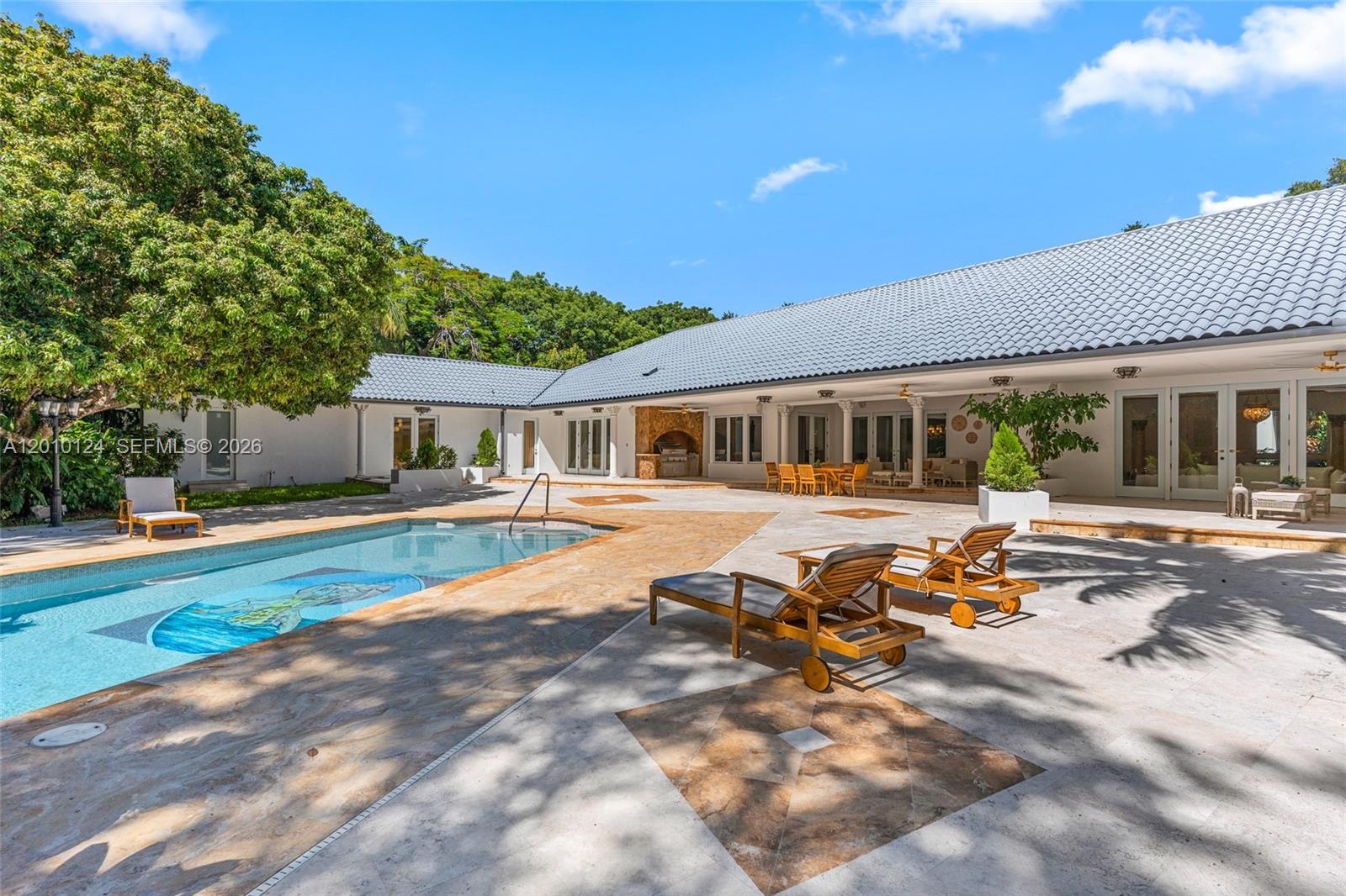 A swimming pool with a patio and lounge chairs sits before a large, single-story house — 9400 Old Cutler Rd, Coral Gables FL 33156, CORAL GABLES, FL