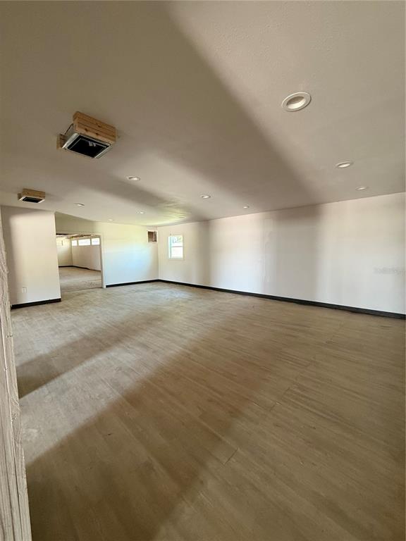 An open, unfurnished room features light wood-look flooring, recessed ceiling lights, and exposed HVAC vents — 109 W BRIDGERS AVENUE, AUBURNDALE, FL