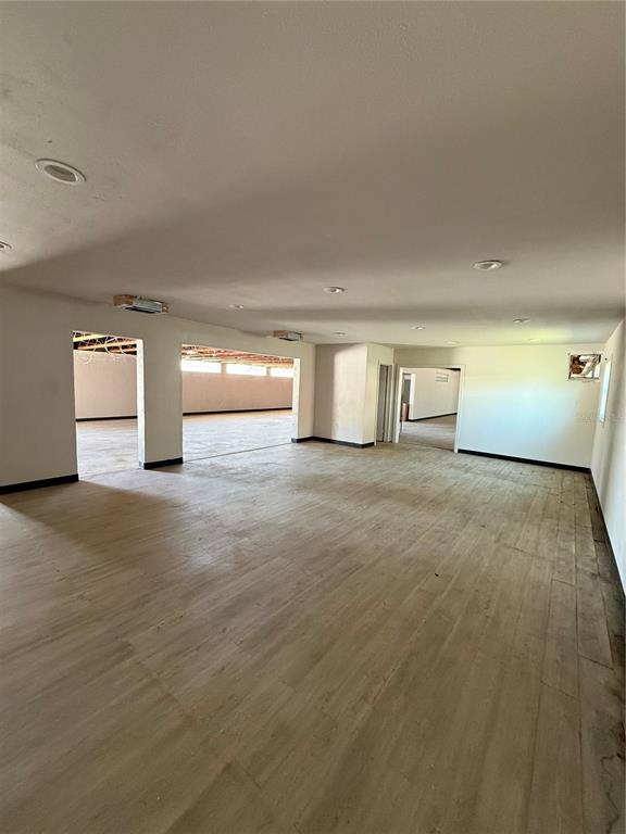 A large, open-concept room with light-colored wood-look flooring and recessed ceiling lights — 109 W BRIDGERS AVENUE, AUBURNDALE, FL