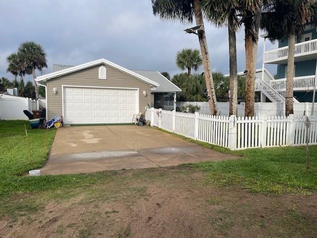 A detached garage with a concrete driveway sits next to a white picket fence — 1907 S DAYTONA AVENUE, FLAGLER BEACH, FL