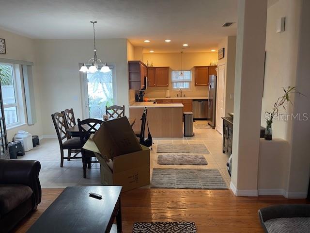 An open-concept kitchen and dining area features light wood cabinets, tile flooring, and a chandelier — 1907 S DAYTONA AVENUE, FLAGLER BEACH, FL