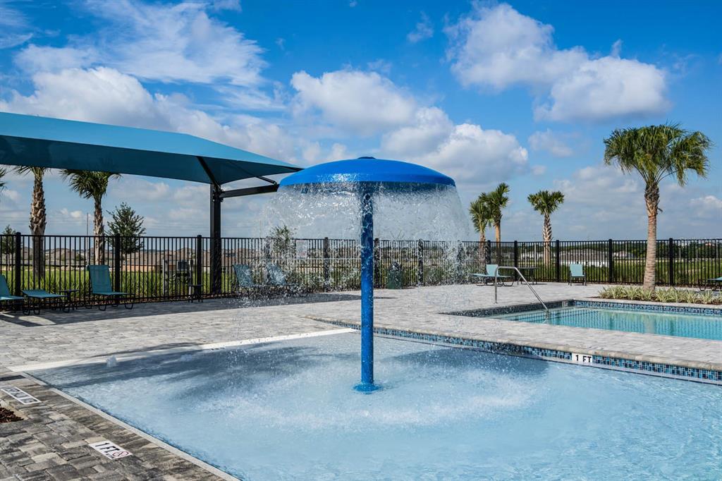 A shallow pool with a mushroom-shaped water feature sits under a blue shade canopy — 2551 MARIAH PLACE, LAKE ALFRED, FL