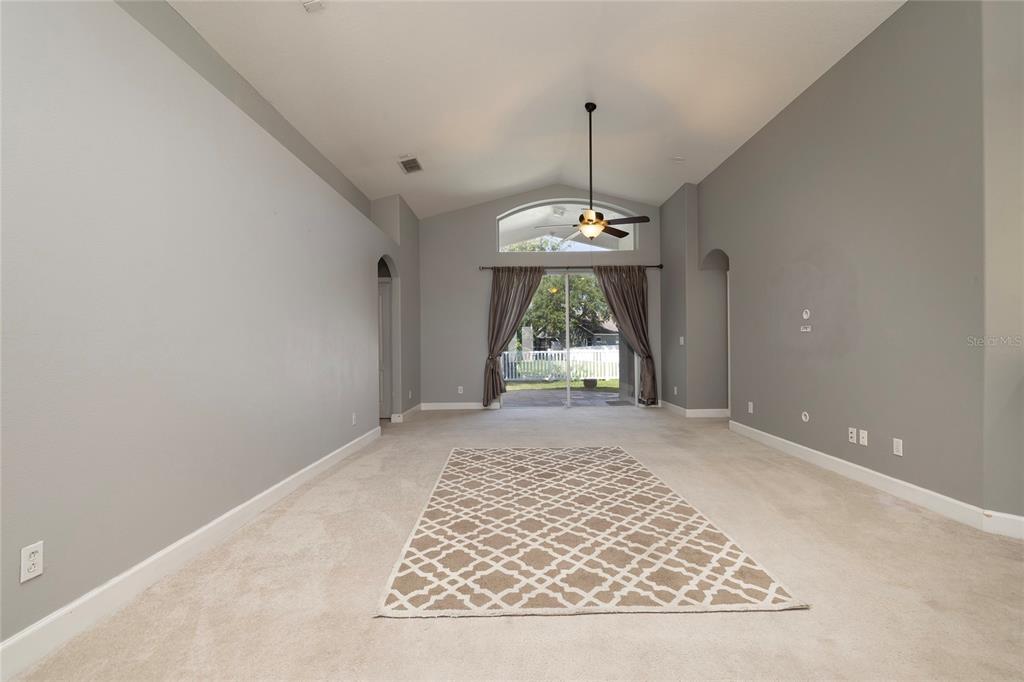 A living room with gray walls, wood-look flooring, a ceiling fan, and sliding glass doors — 219 BAY ARBOR BOULEVARD, OLDSMAR, FL