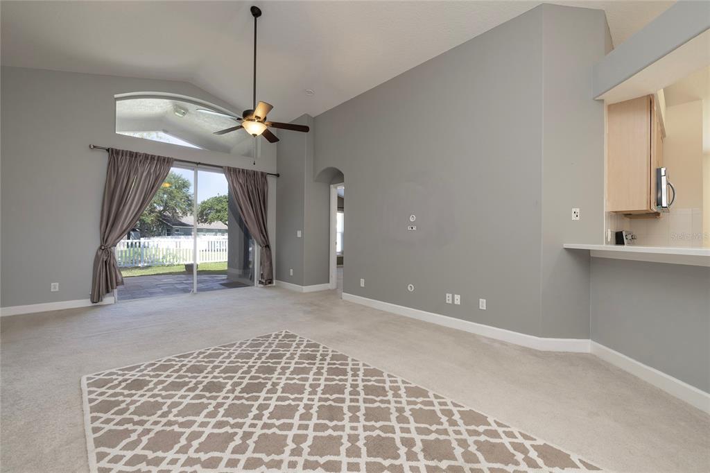 A living room with gray walls, wood-look flooring, a ceiling fan, and sliding glass doors — 219 BAY ARBOR BOULEVARD, OLDSMAR, FL
