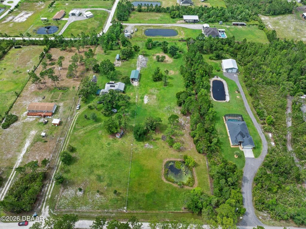 An aerial view shows a large, rectangular grassy lot with a pond and trees — 4034 BUDD ROAD, NEW SMYRNA BEACH, FL