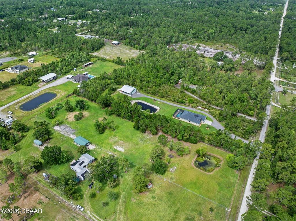 An aerial view shows a rural property with a house, outbuildings, and a pond — 4034 BUDD ROAD, NEW SMYRNA BEACH, FL