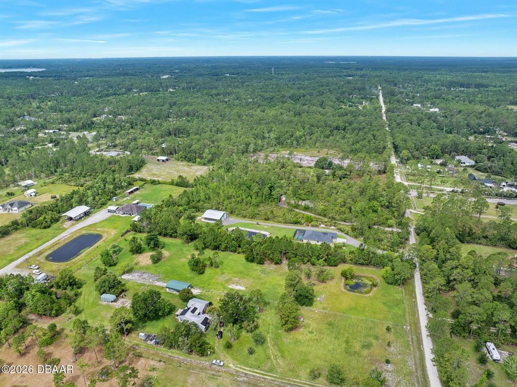 An aerial view shows a large grassy lot with several houses, outbuildings, and two ponds — 4034 BUDD ROAD, NEW SMYRNA BEACH, FL