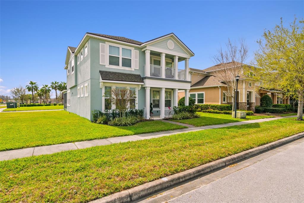 A two-story light blue house with a front porch and balcony sits on a corner lot — 2800 CELLO LANE, KISSIMMEE, FL