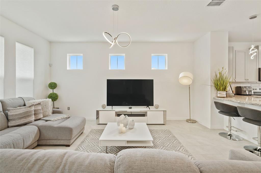 A modern living room features a gray sectional sofa, a white media console, and tile flooring — 2800 CELLO LANE, KISSIMMEE, FL