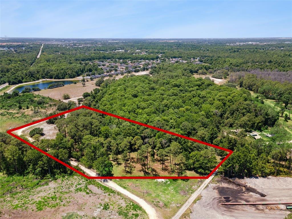 An aerial view shows a wooded plot of land outlined in red near a pond — STATE ROAD 532, DAVENPORT, FL