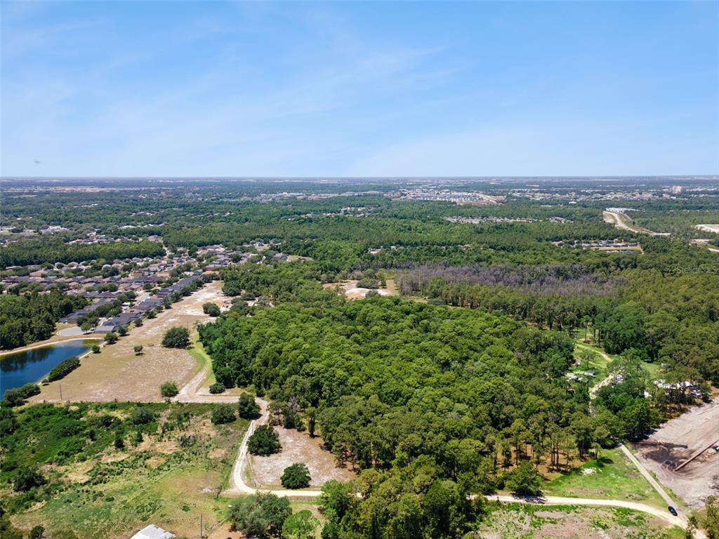 An aerial view shows a large wooded lot bordered by residential neighborhoods and a pond — STATE ROAD 532, DAVENPORT, FL
