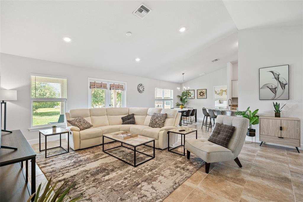 A bright living room features a large sectional sofa, area rug, and open kitchen view — 249 ROTONDA BOULEVARD W, ROTONDA WEST, FL