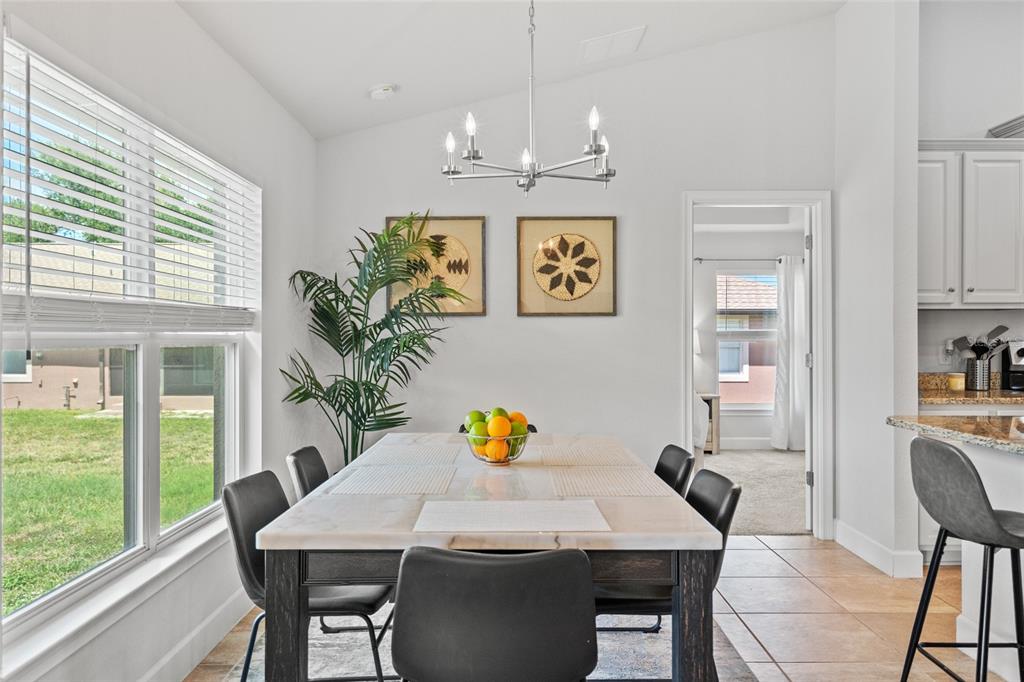 A dining room features a marble-topped table, dark chairs, a chandelier, and a large window — 249 ROTONDA BOULEVARD W, ROTONDA WEST, FL