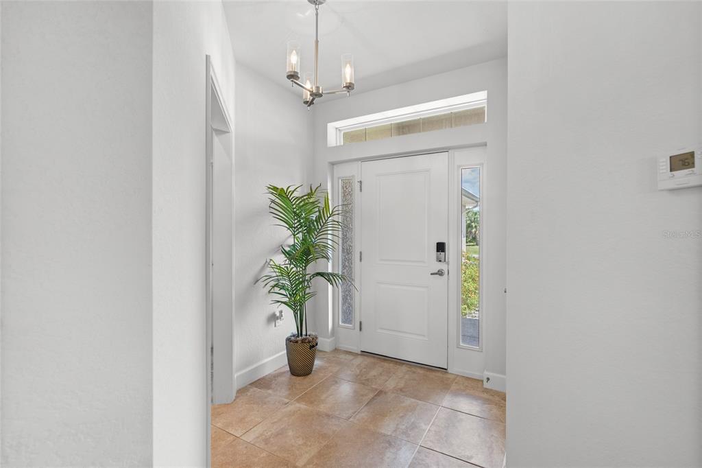 A bright entryway features tile flooring, a potted palm plant, and a white front door — 249 ROTONDA BOULEVARD W, ROTONDA WEST, FL