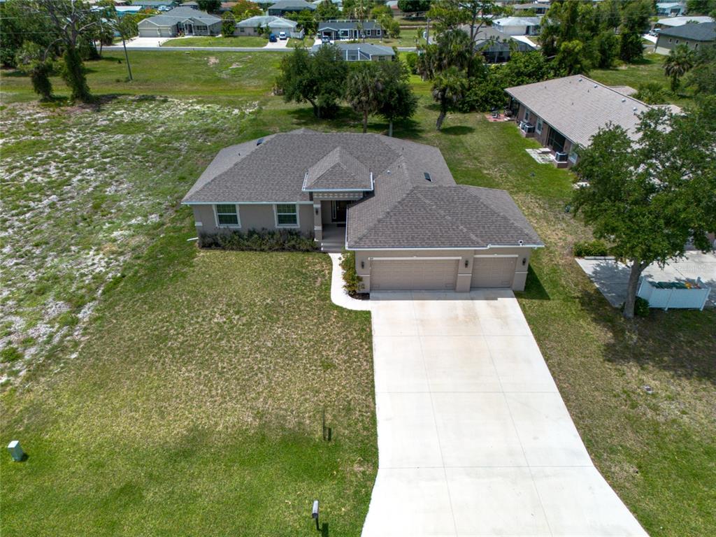 An aerial view shows a single-story house with a shingled roof and concrete driveway — 249 ROTONDA BOULEVARD W, ROTONDA WEST, FL