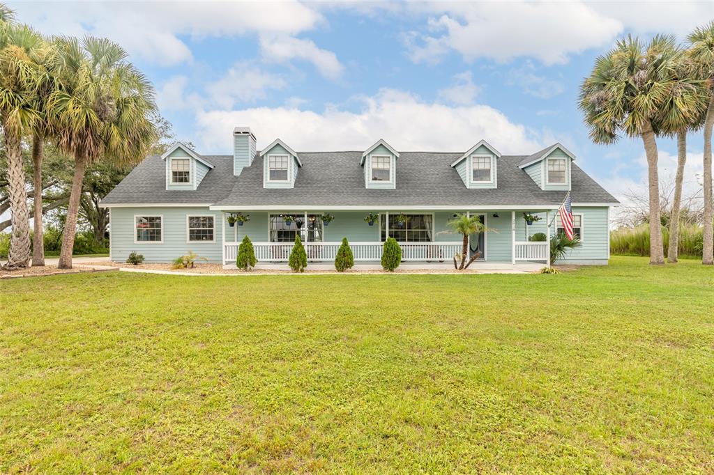 A light blue house with a covered porch and five dormer windows sits on grass — 2018 MONTERO CIRCLE, DELTONA, FL