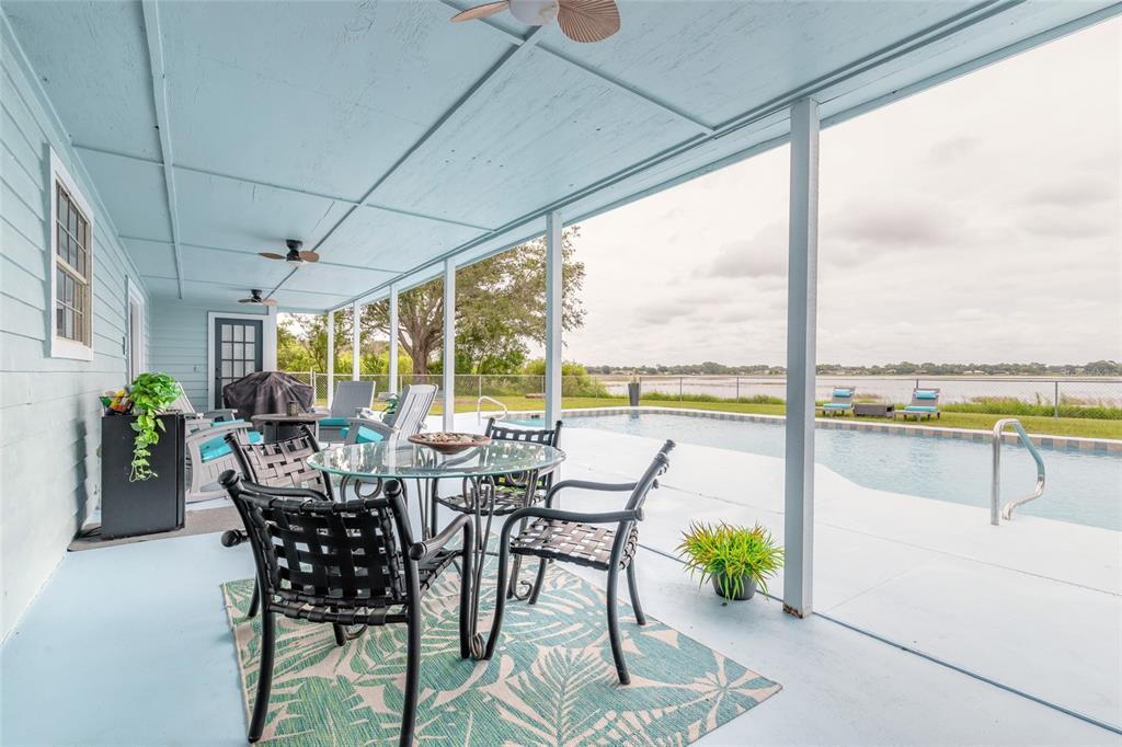 A covered patio features a dining set, ceiling fans, and a view of a swimming pool — 2018 MONTERO CIRCLE, DELTONA, FL