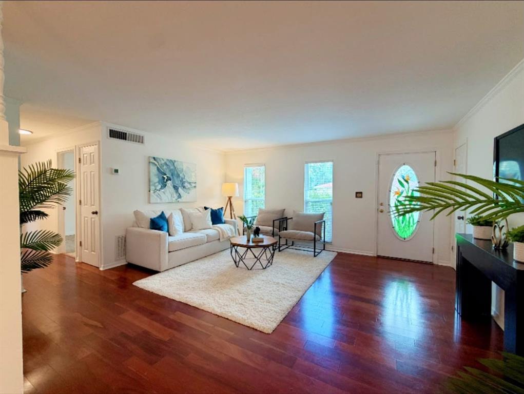 A living room features hardwood floors, a white area rug, a sofa, and a front door — 7514 LAUREL SPRINGS DRIVE, WINTER PARK, FL