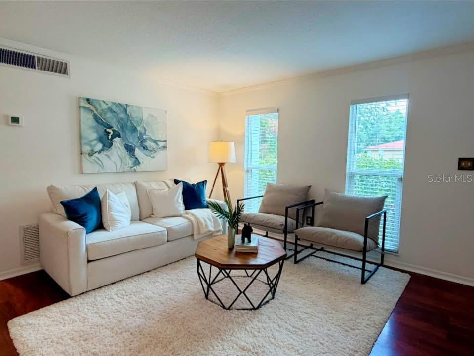 A living room features a white sofa, two armchairs, a hexagonal coffee table, and abstract art — 7514 LAUREL SPRINGS DRIVE, WINTER PARK, FL